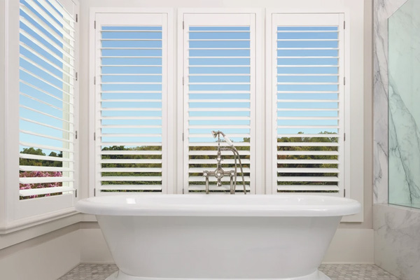 A large, modern bathroom with a freestanding bathtub and a window overlooking a serene outdoor view.