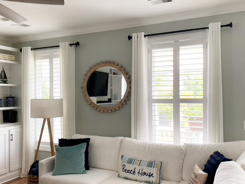 A well-lit living room with a white couch, large windows, and a blue wall.